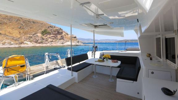 The inviting outdoor area of a Lagoon 560 catamaran offers comfortable seating and a table, perfect for dining or relaxi